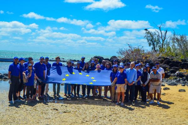 2024 EUBeachCleanup in Mauritius, many people on a beach holding an EU flag