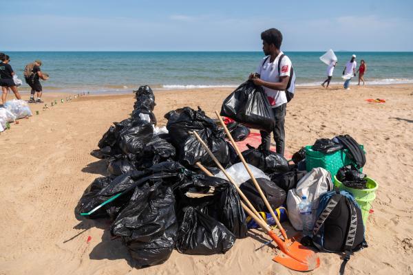 2024 EUBeachCleanup in Tunis, Tunisia. People on the beach picking up rubbish and several black bags filled with rubbish